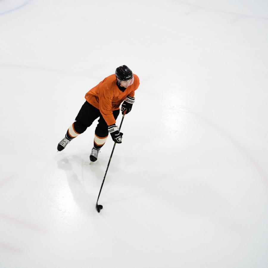 Aerial view of a hockey player skating on the ice, move the puck with his stick.